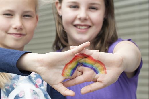 zwei Mädchen mit einem aufgemalten Regenbogen auf ihren Handflächen